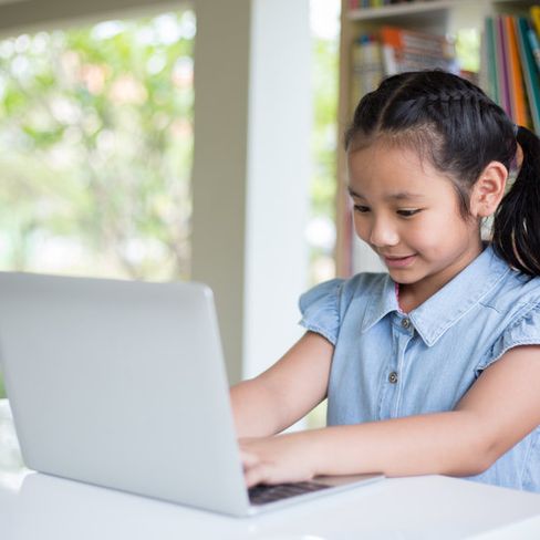 niña escribiendo en ordenador portátil